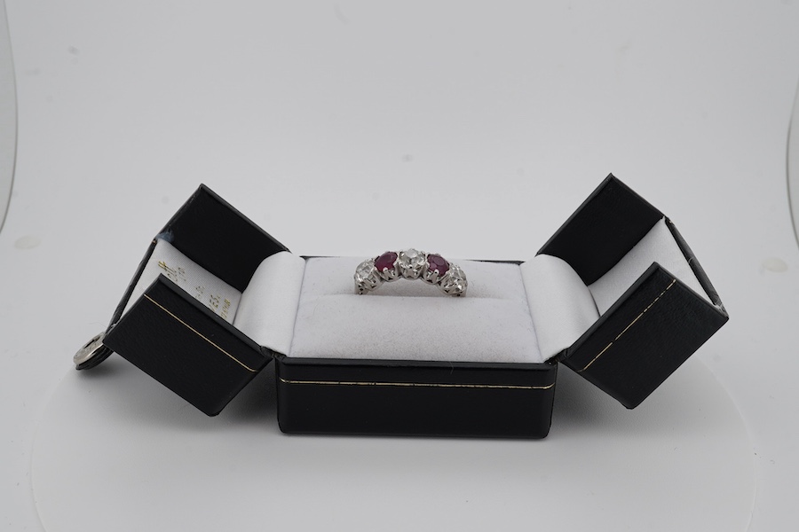 A ruby and diamond five-stone ring, set with an alternating sequence of antique cushion-shaped diamonds totalling approximately 1.50 carats, spaced with circular-cut rubies, mounted in platinum, size M (sizing beads), Br